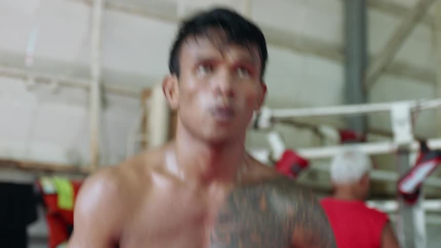 A boxer jumps up and down and takes in deep breaths while standing outside the ring