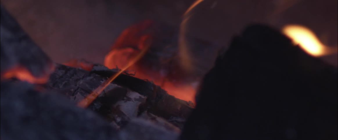 Pieces of wood glow orange as they burn in a campfire