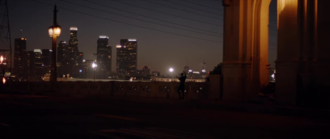Silhouette of a woman performing modern dance on the streets of a city at night
