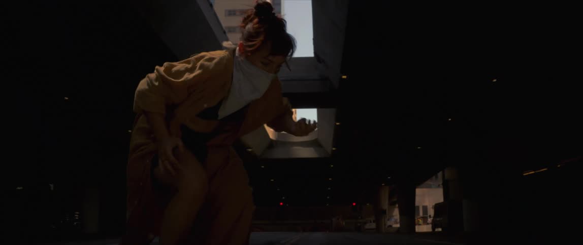 A woman wearing a scarf around her face slides on the floor in a dance mood