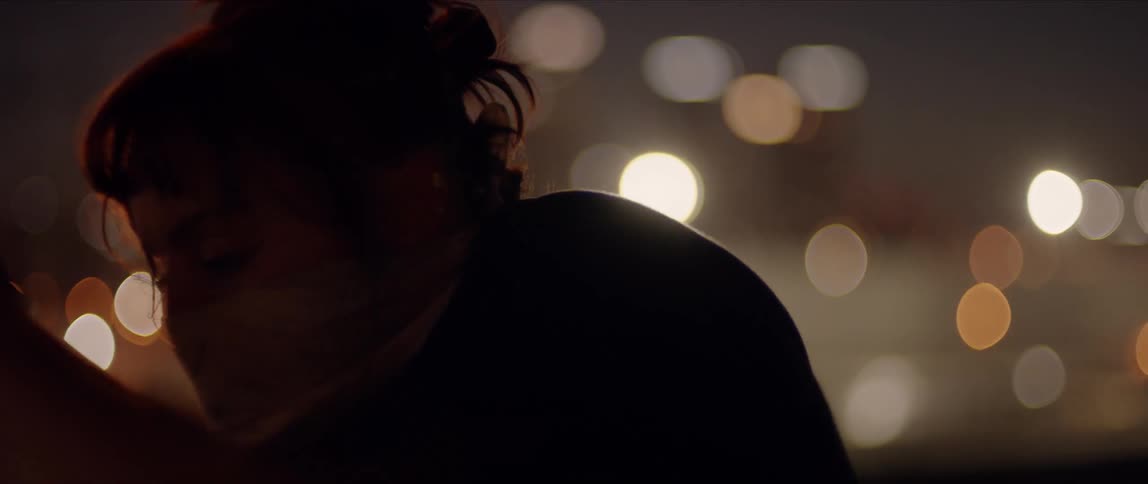 A woman with a mask doing contemporary dance poses at night in a city