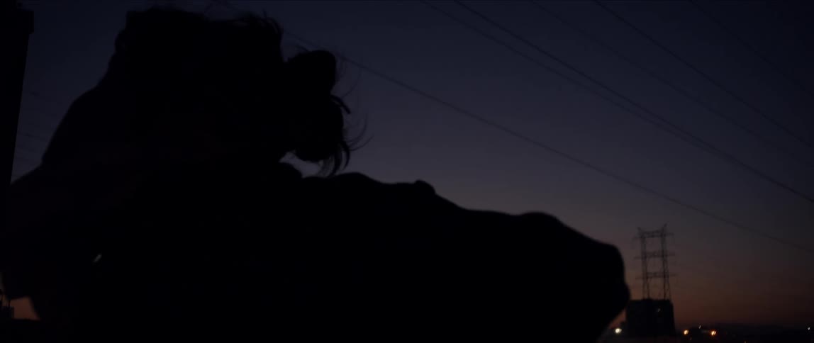 Silhouette of a young woman dancing in front of the city skyline at evening
