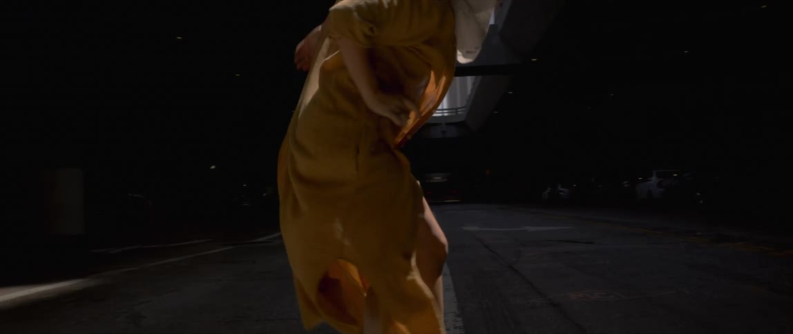 A woman dances alone on an empty city street at night