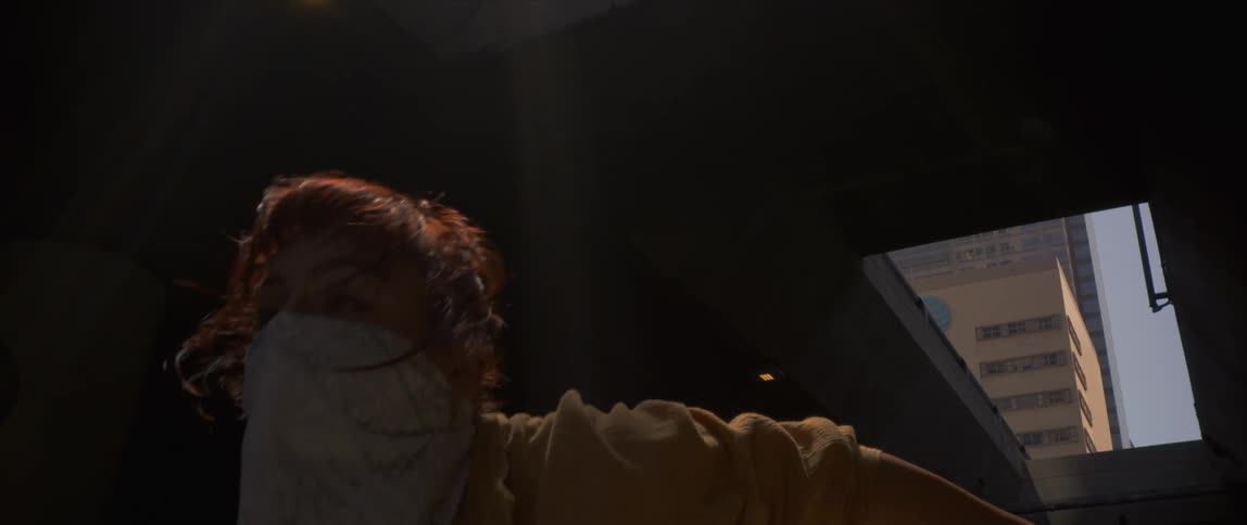 Woman wearing a face mask dancing under a bridge in the city at evening