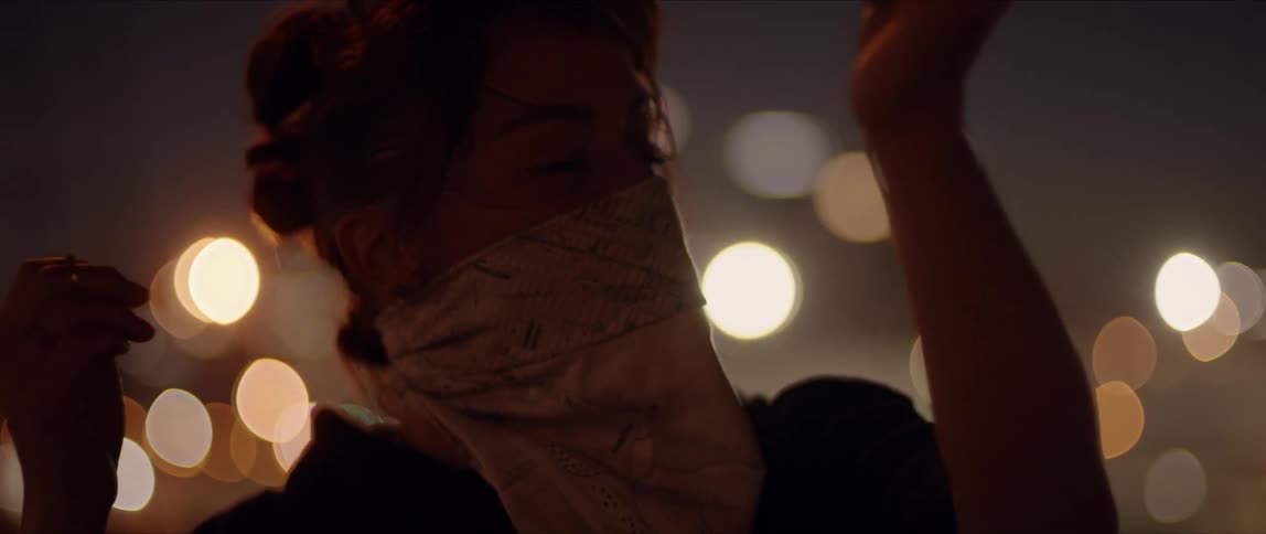 Young woman wearing a face mask dancing in front of the city skyline at night