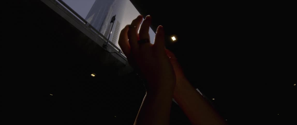 Woman waving hands in front of the reflected sunlight on a building