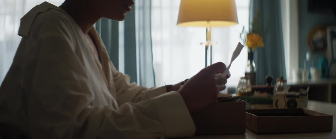 Young woman opening a letter found in a box in a dimly lit room