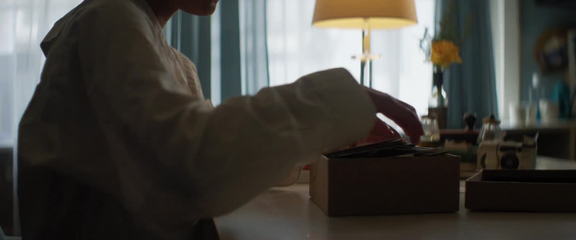 A woman at home opens a box and takes papers out and reads one of them