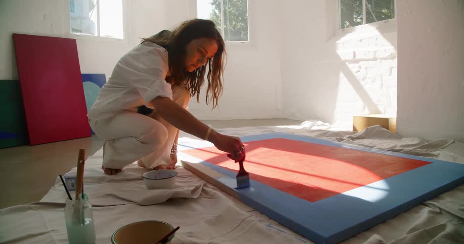 White woman painting a frame inside a art room
