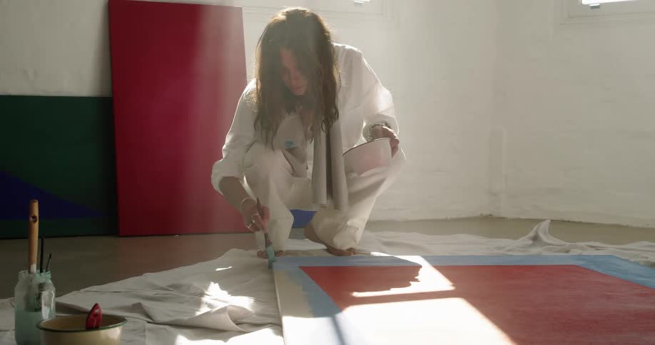 A woman is painting a picture indoors during the day