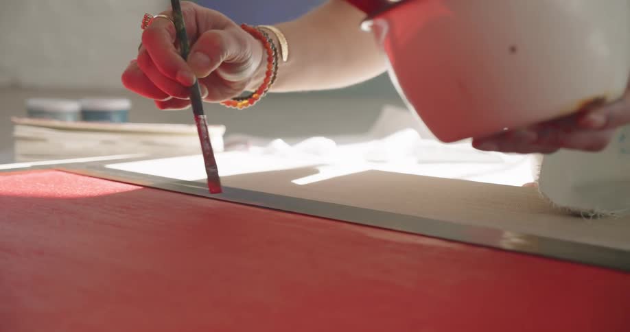 A person is painting a canvas red