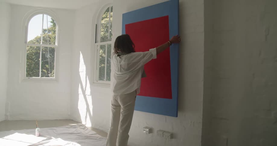 A woman holding up a canvas