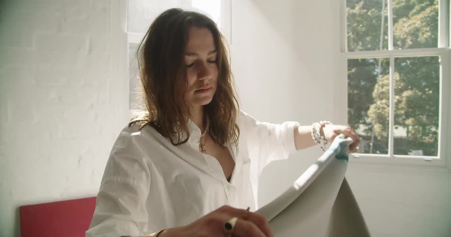 Young painter places a piece of cloth over her shoulder in a room