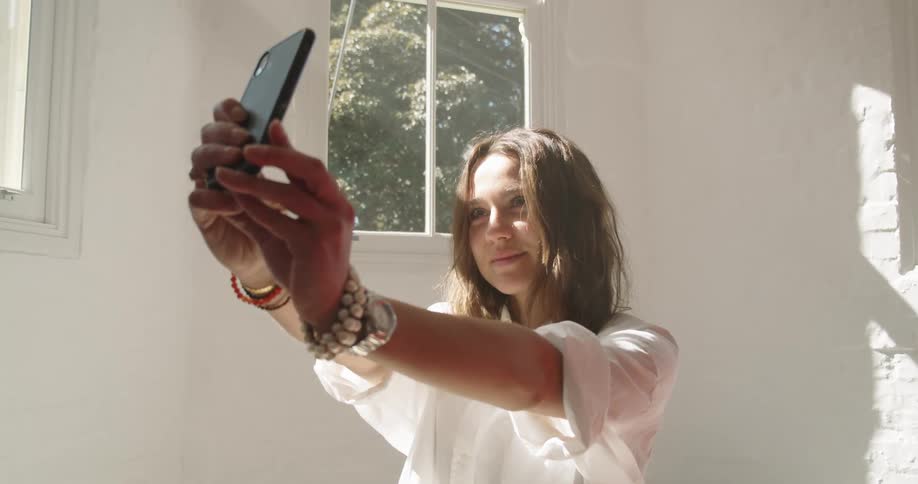 A woman takes a selfie in the bright room