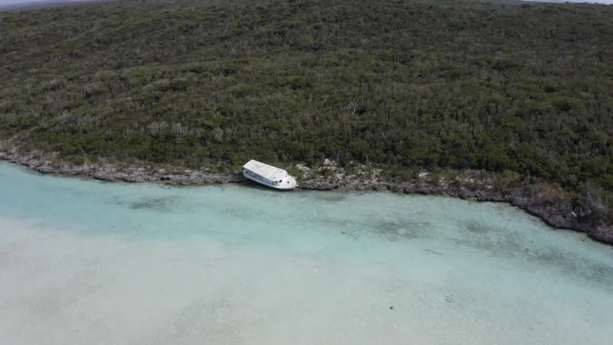 Aerial view of a white boat parked up on a shore on an island at daytime