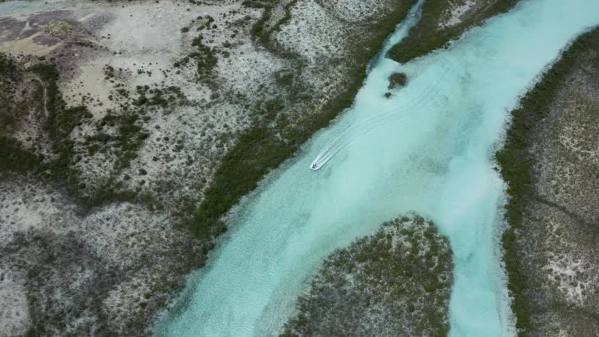 An aerial view of a boat driving down a river