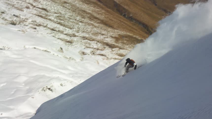 A person skis down a snowy slope of a mountain