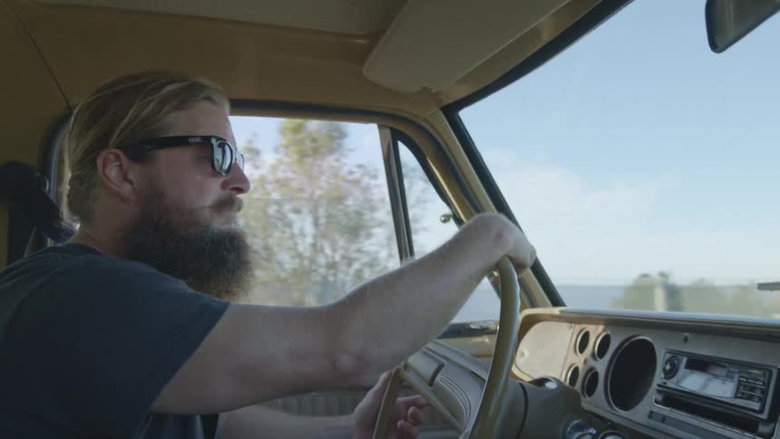 Bearded man wearing sunglasses and driving a car