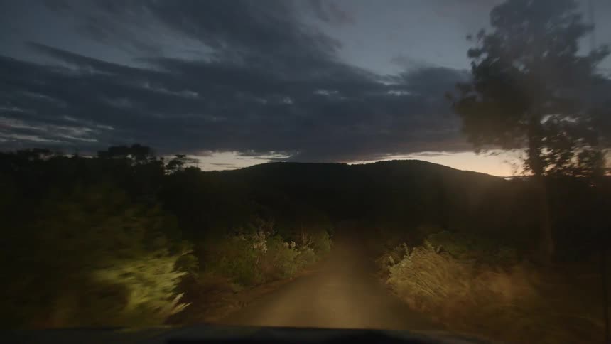 A car driving down a dirt road at night