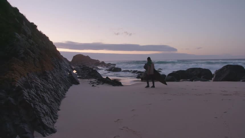 A person carrying a large shaped object across a beach