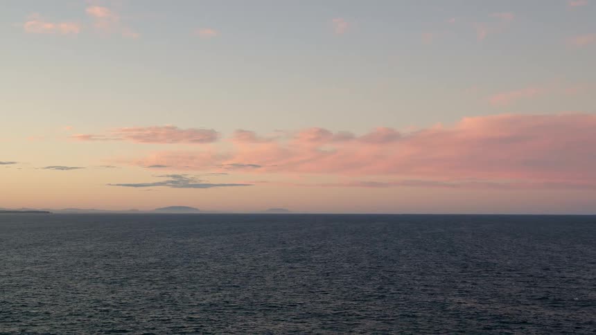 Landscape of ocean with blue and pink sky with clouds