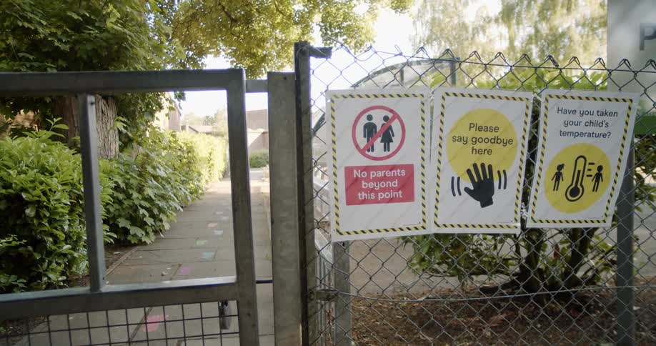 Various signs on the wired fence near the entrance to a school