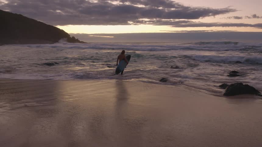 A man carries his surf board in to the waves