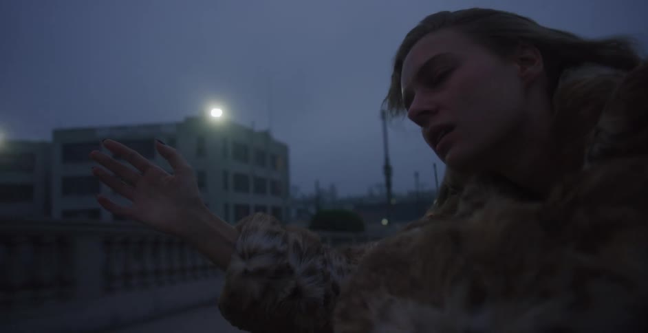 Young woman feels the wind in her hair peeking out of a car window in the city at night