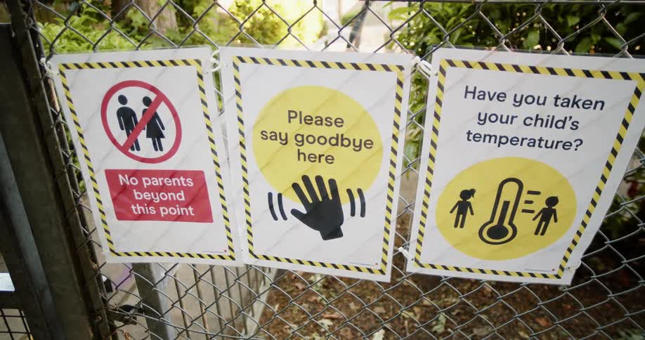 Signs advising safe social distancing practices posted on a fence outside at daytime