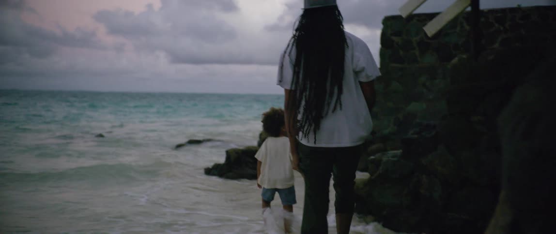 Father and son walk along the coast of a beach and head up some stairs