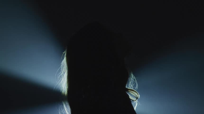 Silhouette of a woman standing in front of a flashing light