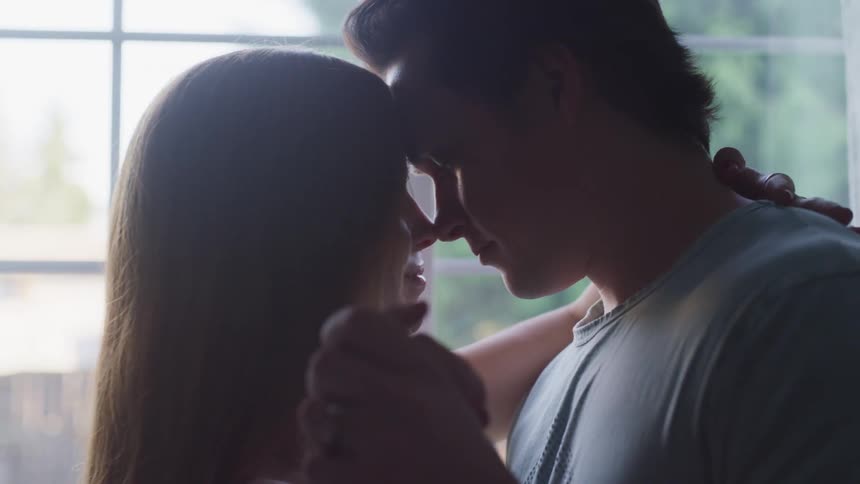 Husband and wife are dancing next to a window in spring