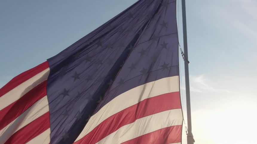 Sunlight shines through the fabric of a waving american flag