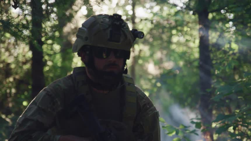 A soldier with a helmet sunglasses and a rifle in a forest