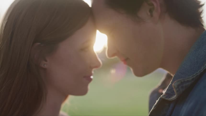 Man and woman facing and staring each other while touching their heads in a romantic way