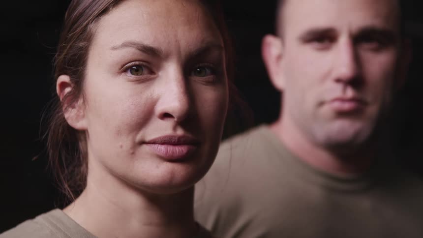 A woman and man in tan shirts stare into the camera