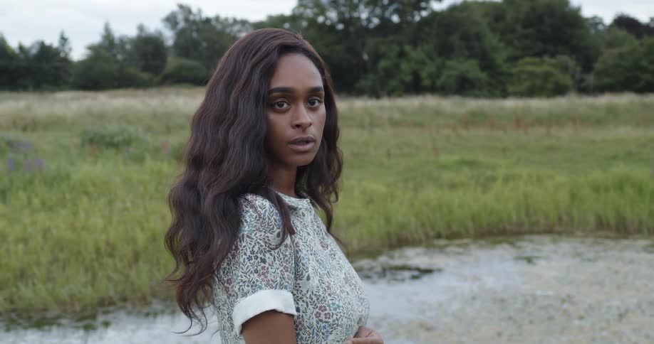 A woman standing in a field looking into the distance