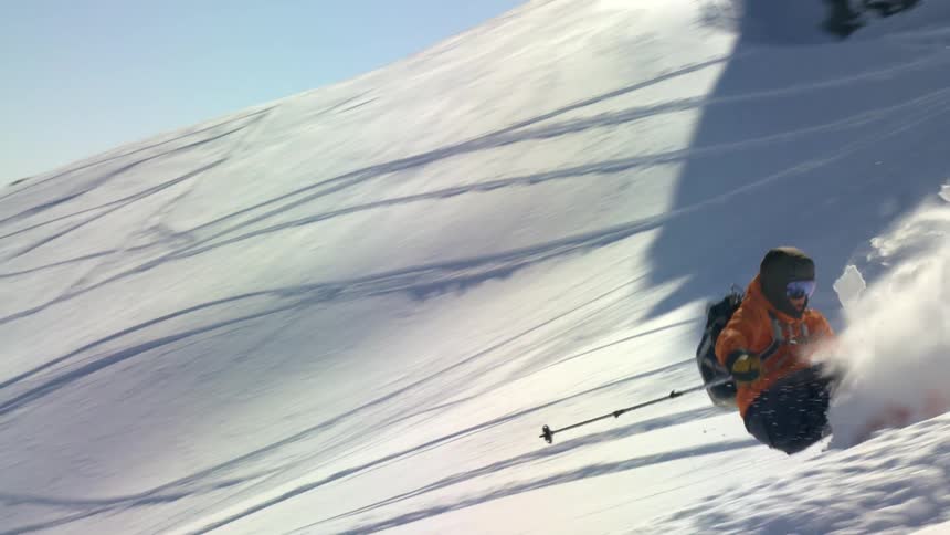 A man skis down a snowy mountain ski slope takes a tumble then gets back up and continues downward