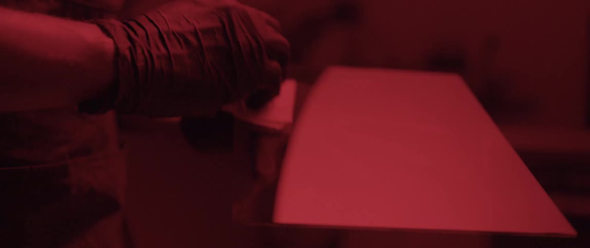 Photographer preparing a sheet of glass to develop a picture in a dark room