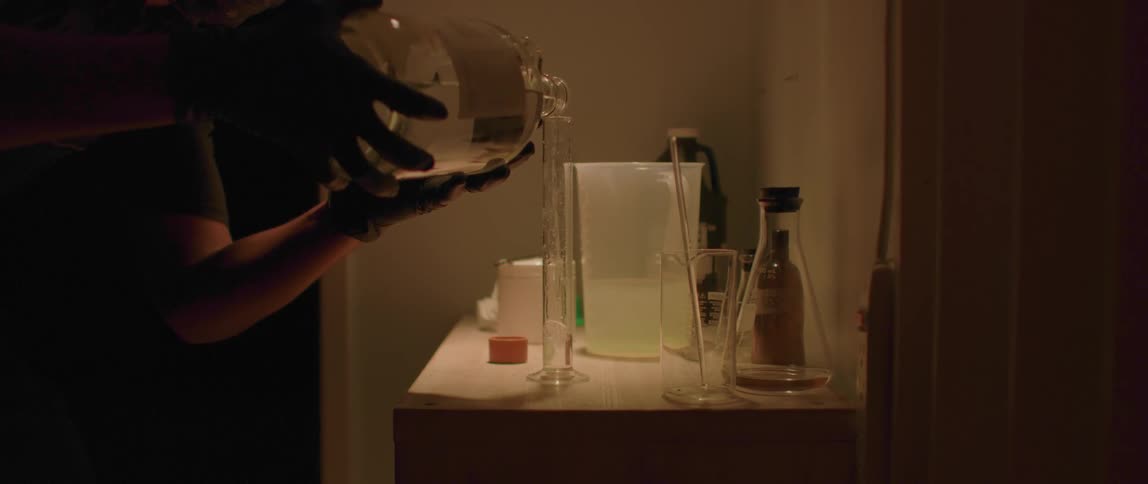 A man in a lab pours liquid in to a test tube