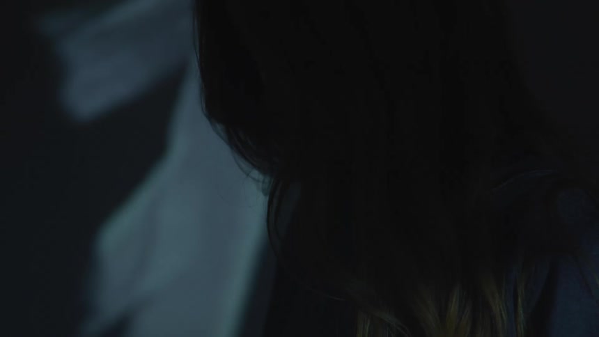 A female stands in a room with flashing lights with her head down