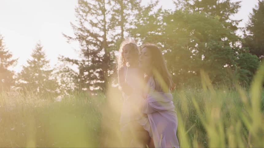 Mother and daughter stand in a field during the day and bubbles
