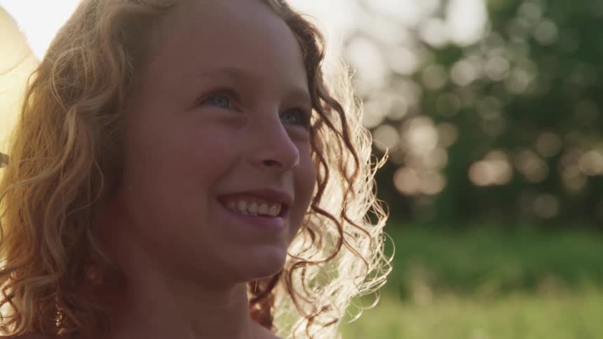A girl standing outdoors in a field smiles