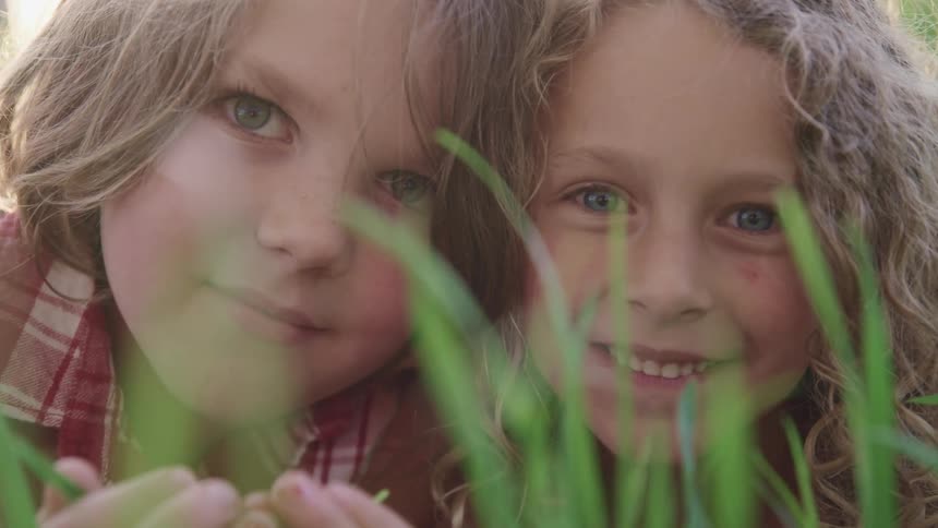 A young boy and girl lie in the grass and smile