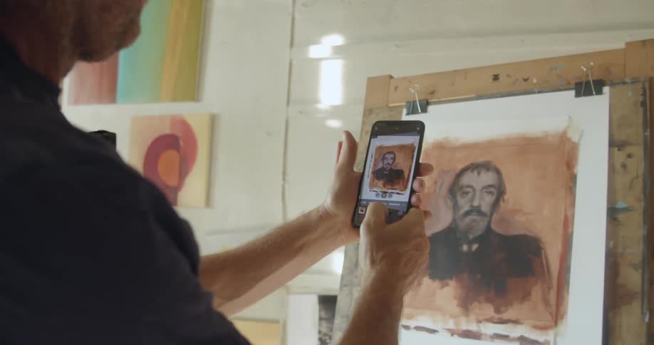 Man takes a photo of a painting with a smart phone