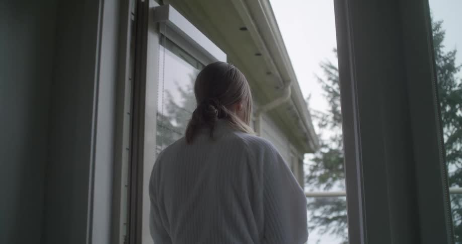 A woman walks out of her house and on to her balcony in her robe