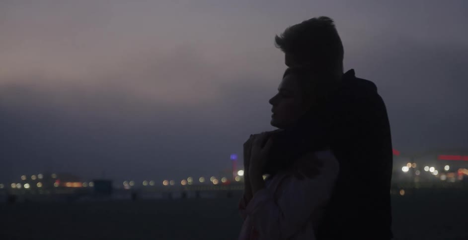 A man and woman hugging each other while on a beach