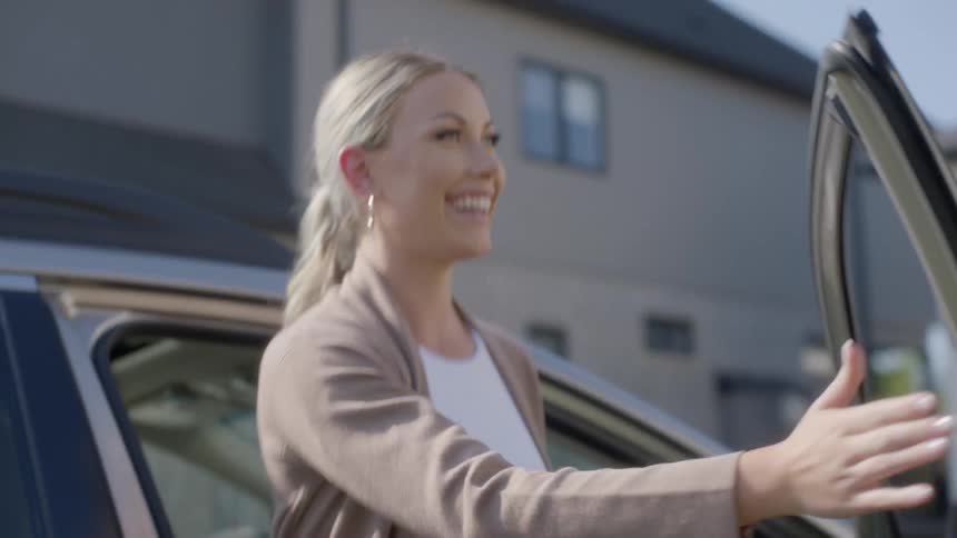 White woman getting out of a car and smiling