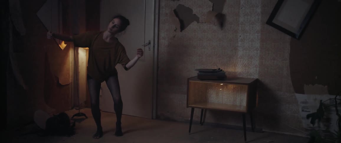 White woman dancing alone inside a room next to the door at the night