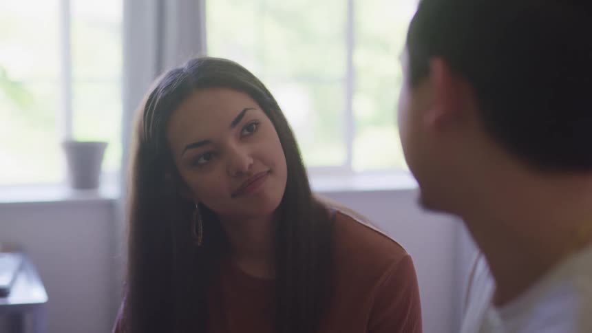A woman sitting next to a man in a room looking at him and smiling